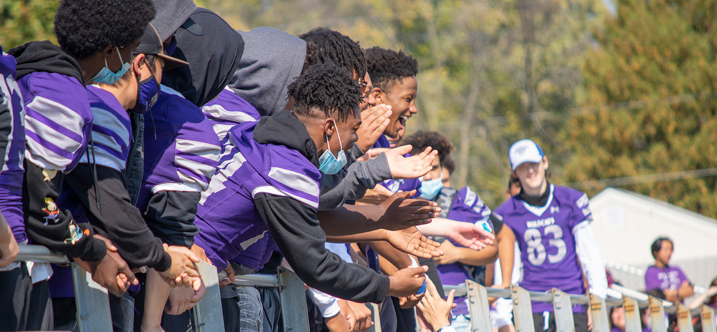 Green Bay West High School football players cheering at school event.