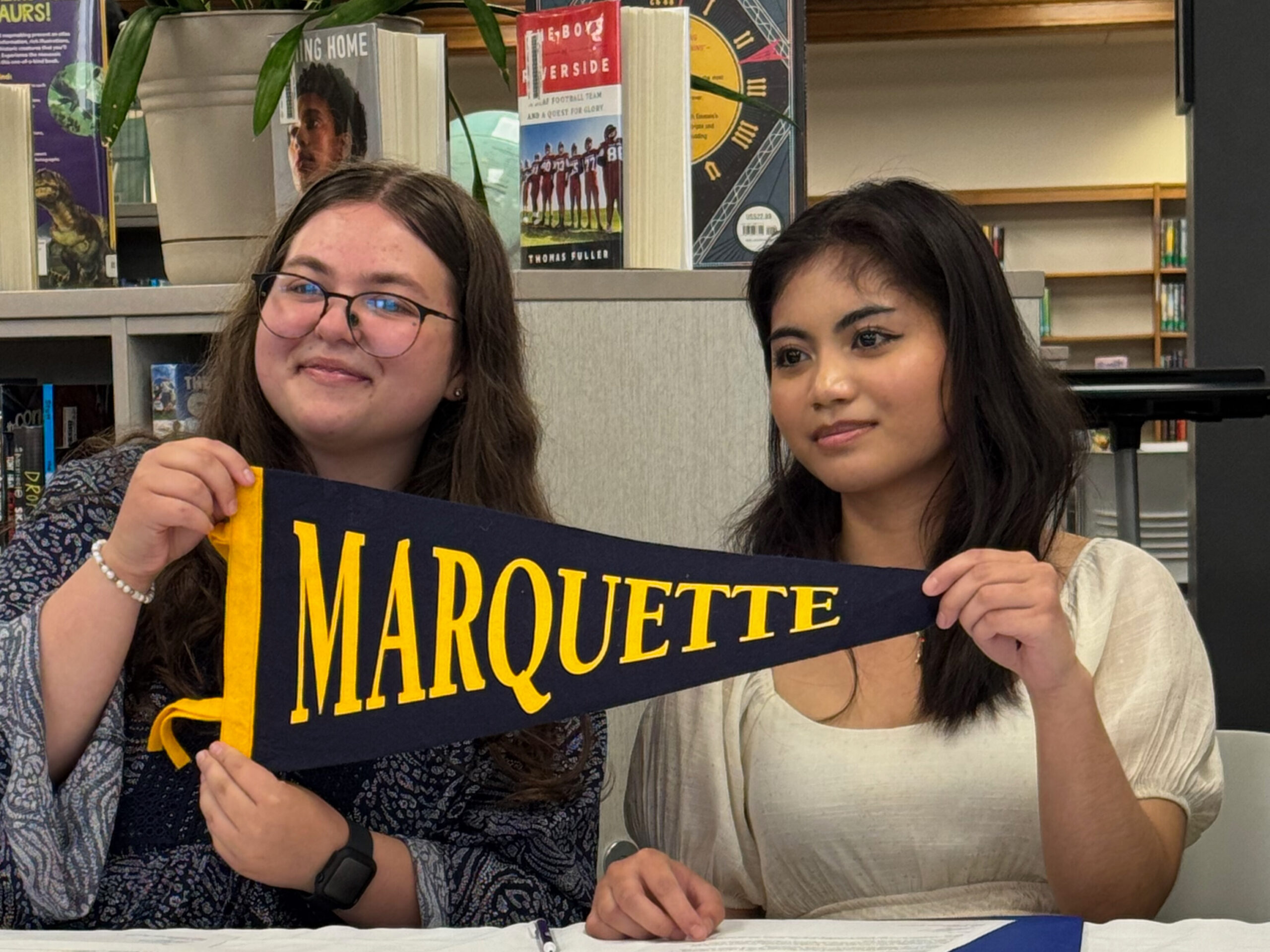 Kai Alcaide and Chloe Burton hold a Marquette University pendant.